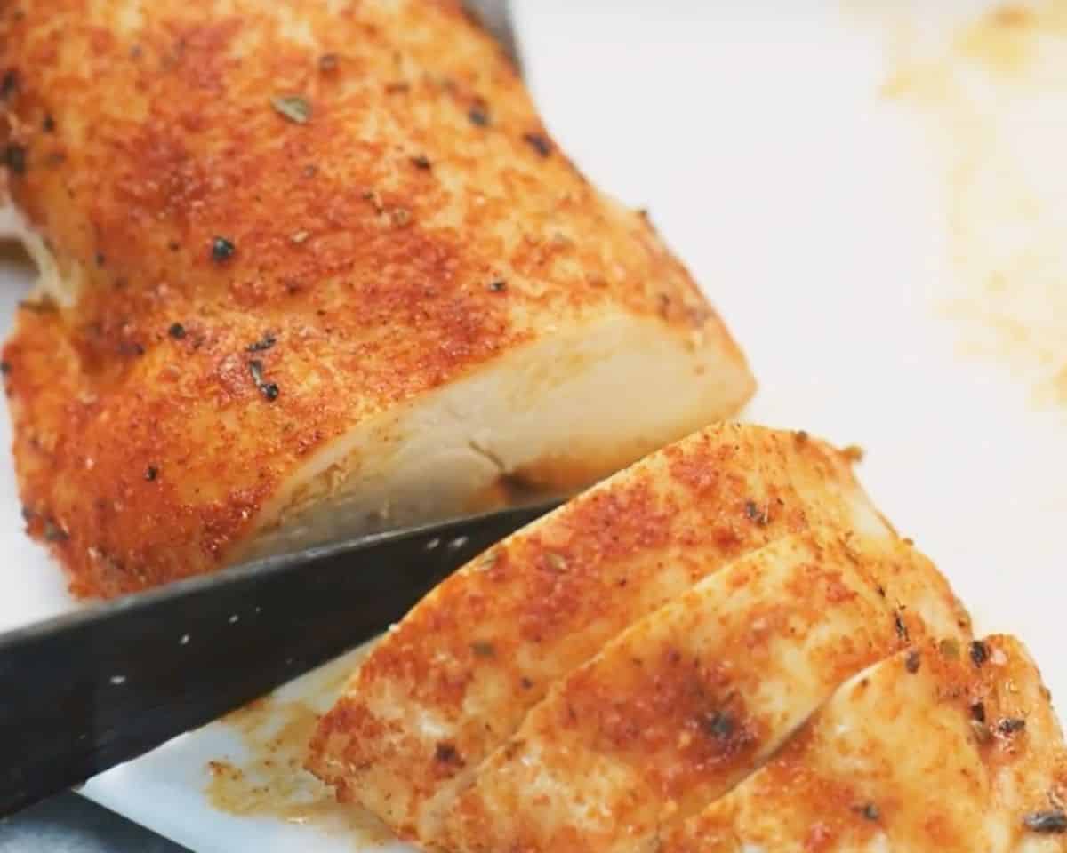 Close up of juicy baked chicken breast being sliced to show the moist interior and seasoned crust - 12