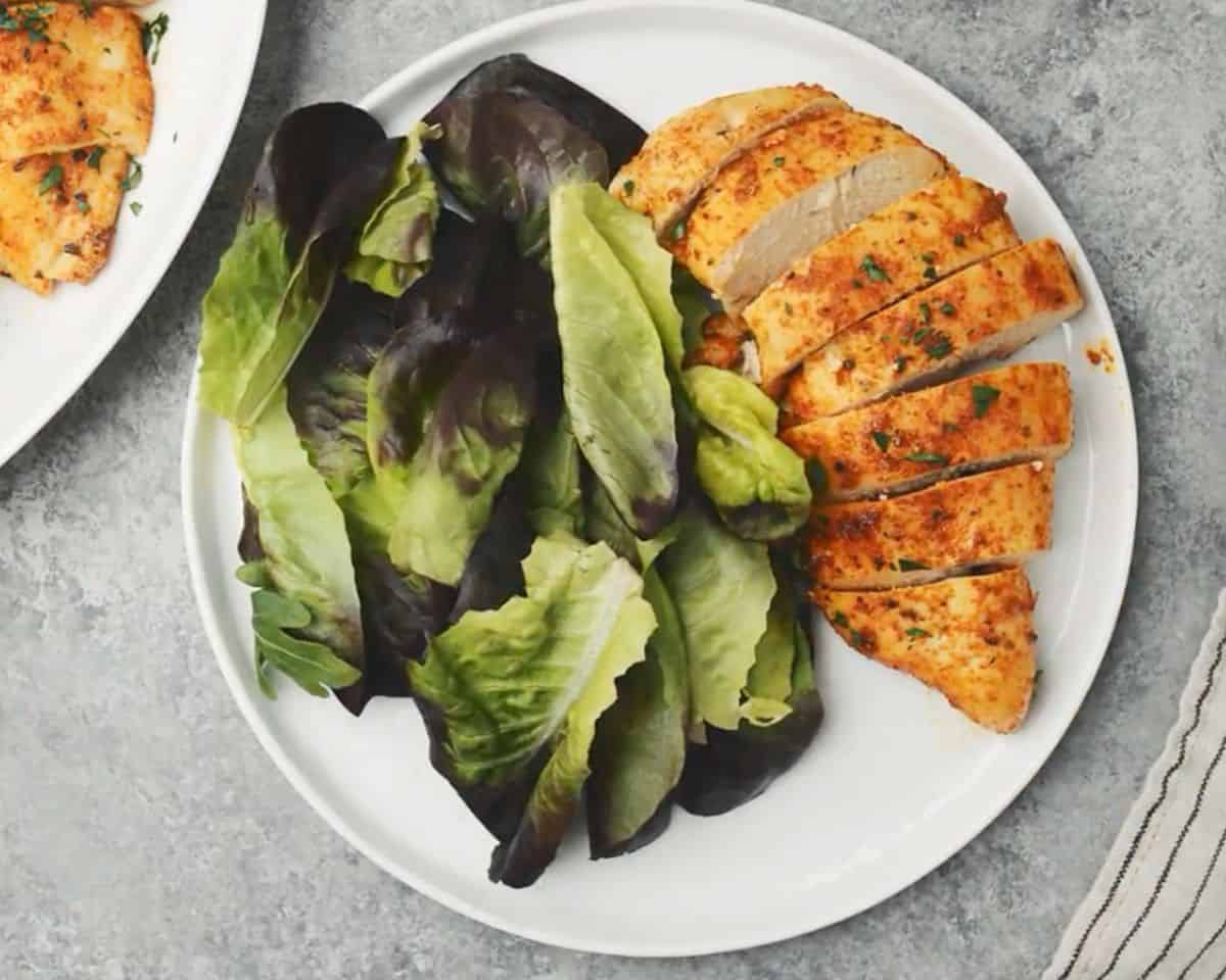 Baked chicken breast served with fresh butter lettuce on a white plate - 13