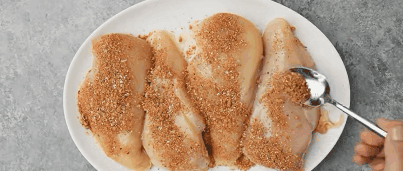 Coating the chicken breasts with seasoning.