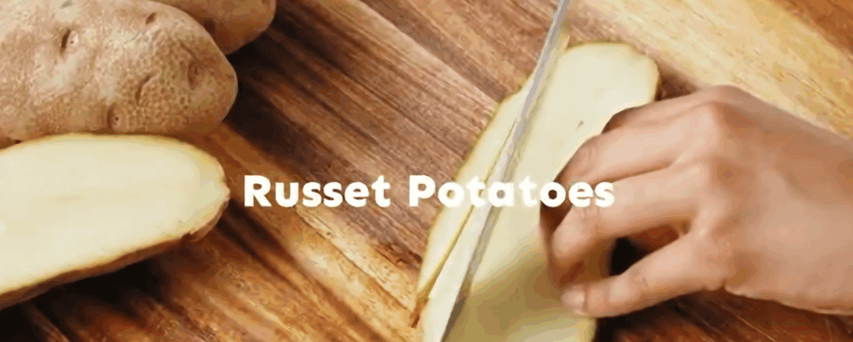 Cutting a potato on a wooden cutting board.