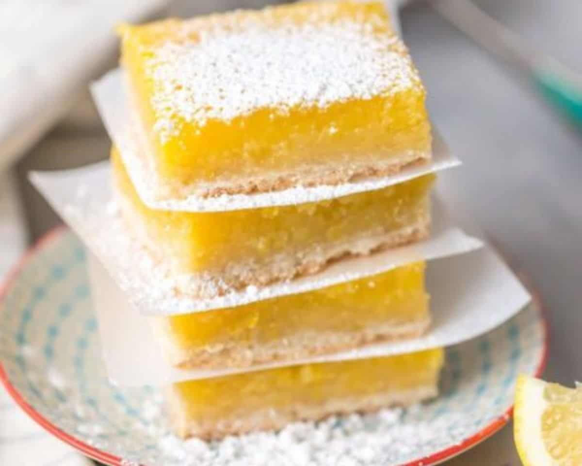 Stack of gluten-free lemon bars with buttery shortbread crust and bright lemon filling, dusted with powdered sugar and served on a plate
