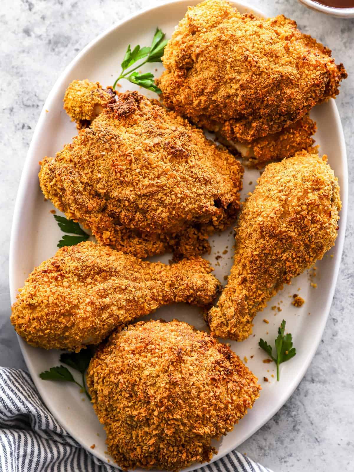 overhead view of 5 pieces of air fryer fried chicken on a white oval serving platter.