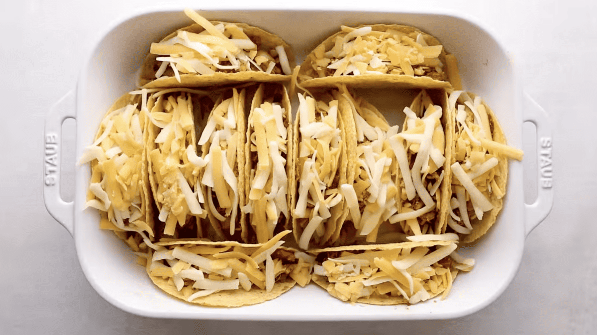 Baked chicken tacos in a white dish.