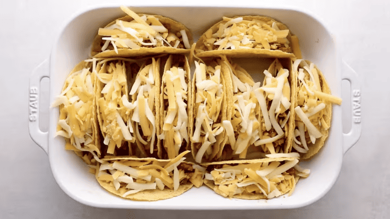 Baked chicken tacos in a white dish.