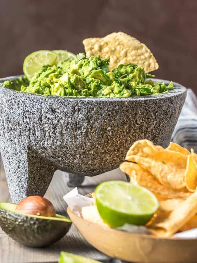Bowl filled with guacamole next to a bowl of chips