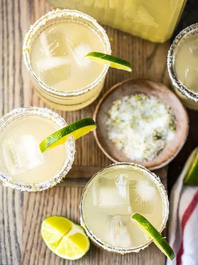 This BEST MARGARITA RECIPE is the only recipe for margaritas you will ever need! This Perfect Margarita Pitcher Recipe is perfect for serving a crowd, made with simple and fresh ingredients, and utterly delicious. There has never been a more perfect margarita! We have written the margarita recipe to serve one or as many as 12. You decide how many of the BEST Margaritas you want to share. overhead shot of margaritas with limes and salt