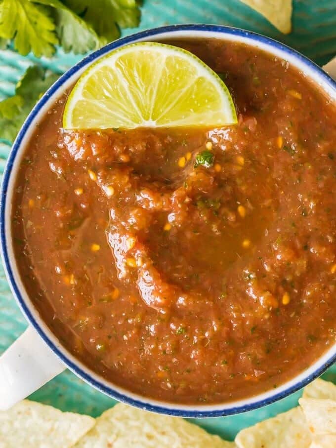 close up on a bowl of restaurant style salsa topped with a lime slice