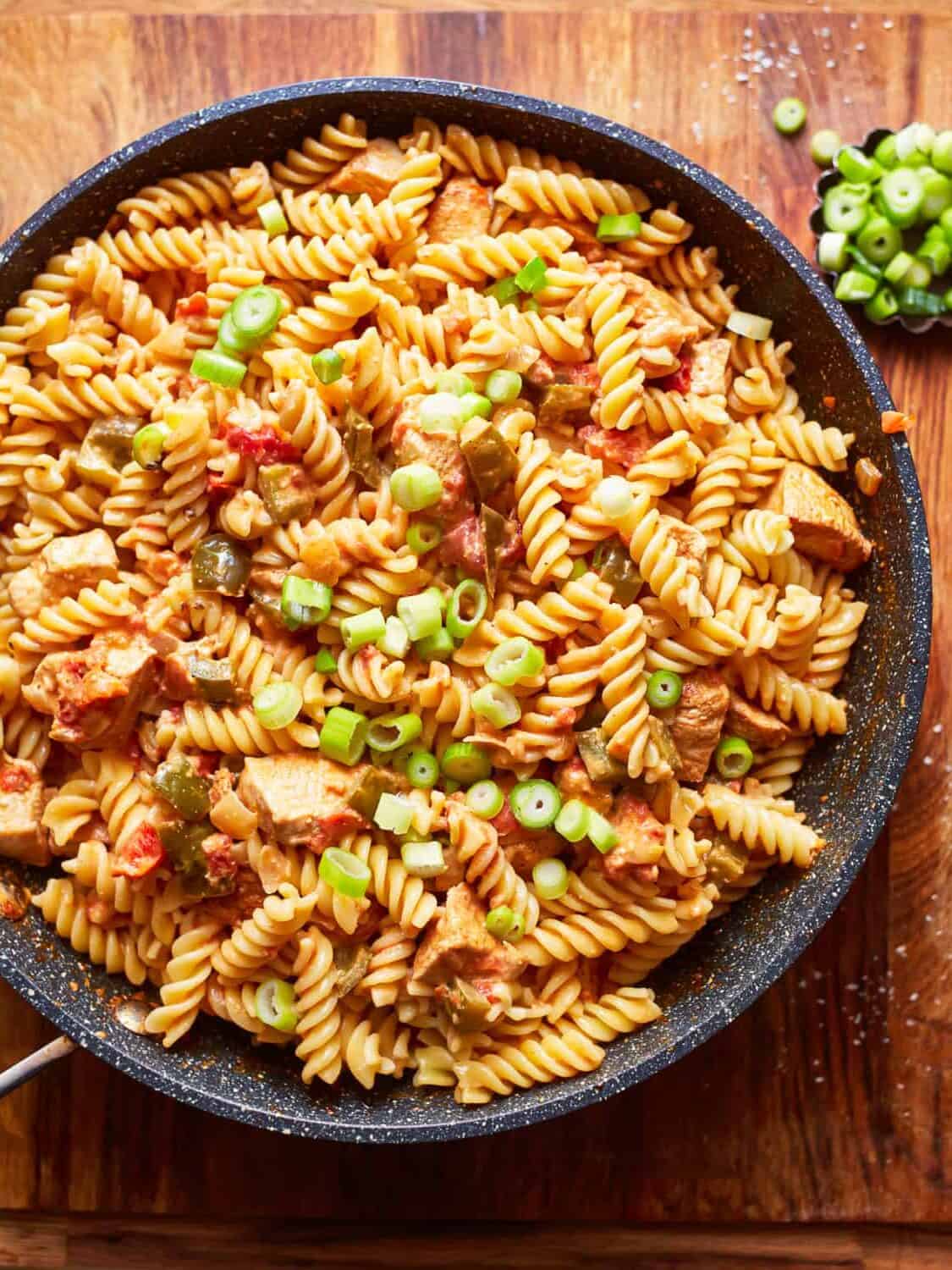 overhead view of cajun chicken pasta filled with diced veggies and bites of chicken, in a pan set on a tabletop