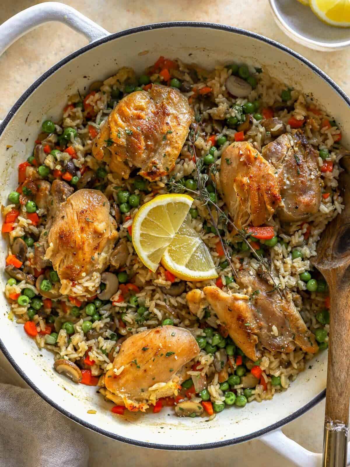 overhead view of chicken and rice in a dutch oven with a wooden spoon.