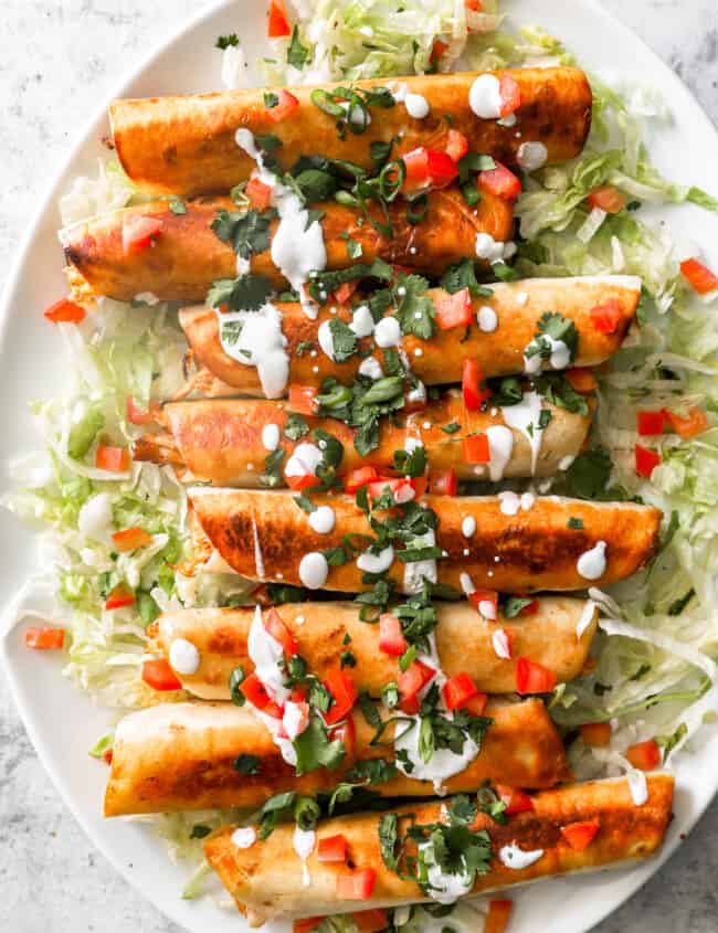 overhead view of 8 chicken flautas on an oval serving platter.