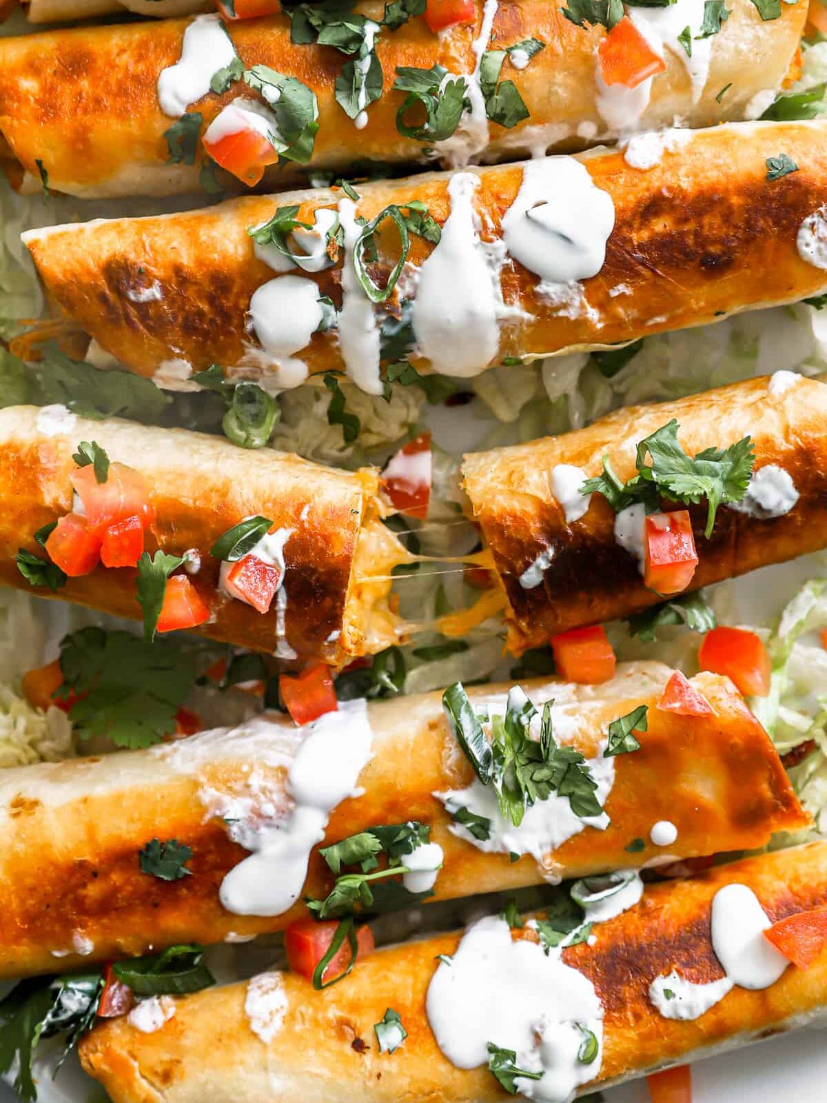 close up overhead view of chicken flautas, one is halved.
