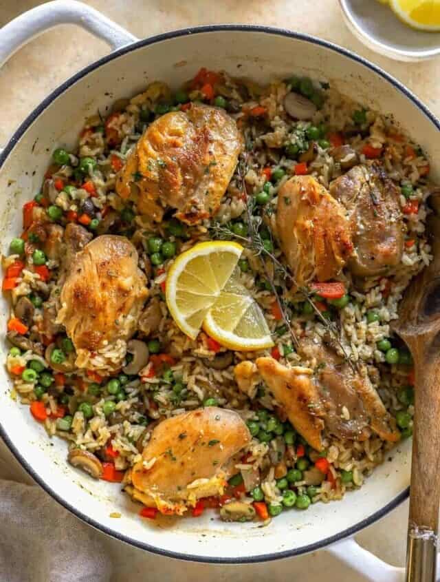 overhead view of chicken and rice in a dutch oven with a wooden spoon.