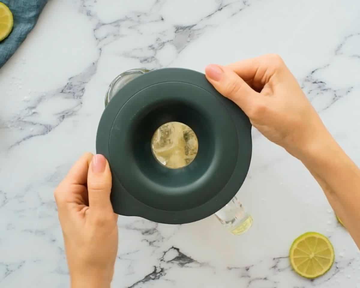 Placing the lid on a blender pitcher filled with tequila, lime juice, Cointreau, agave nectar, and ice for frozen margaritas.
