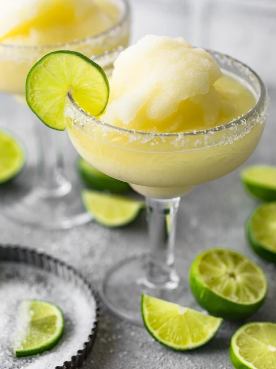 two margarita glasses with limes and ice.