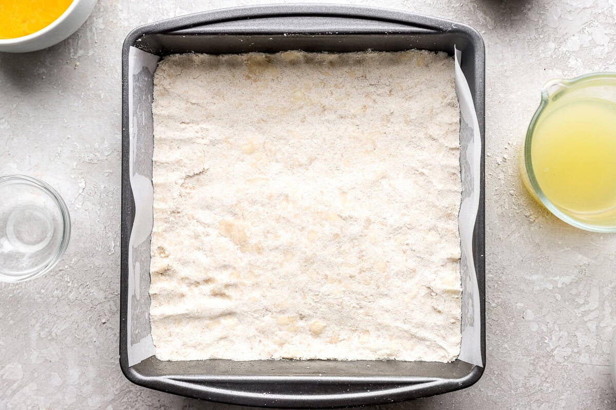 Pressing gluten-free shortbread crust into lined baking pan before baking