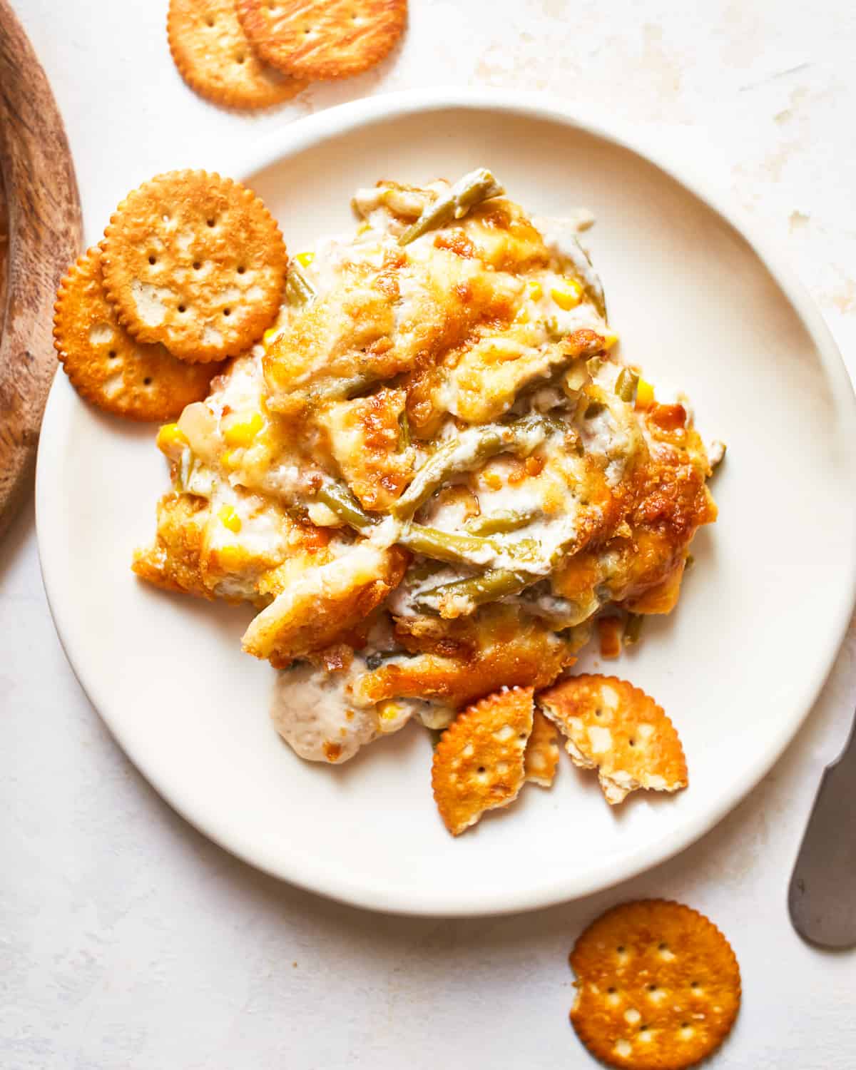 a serving of green bean corn casserole on a small plate with ritz crackers 