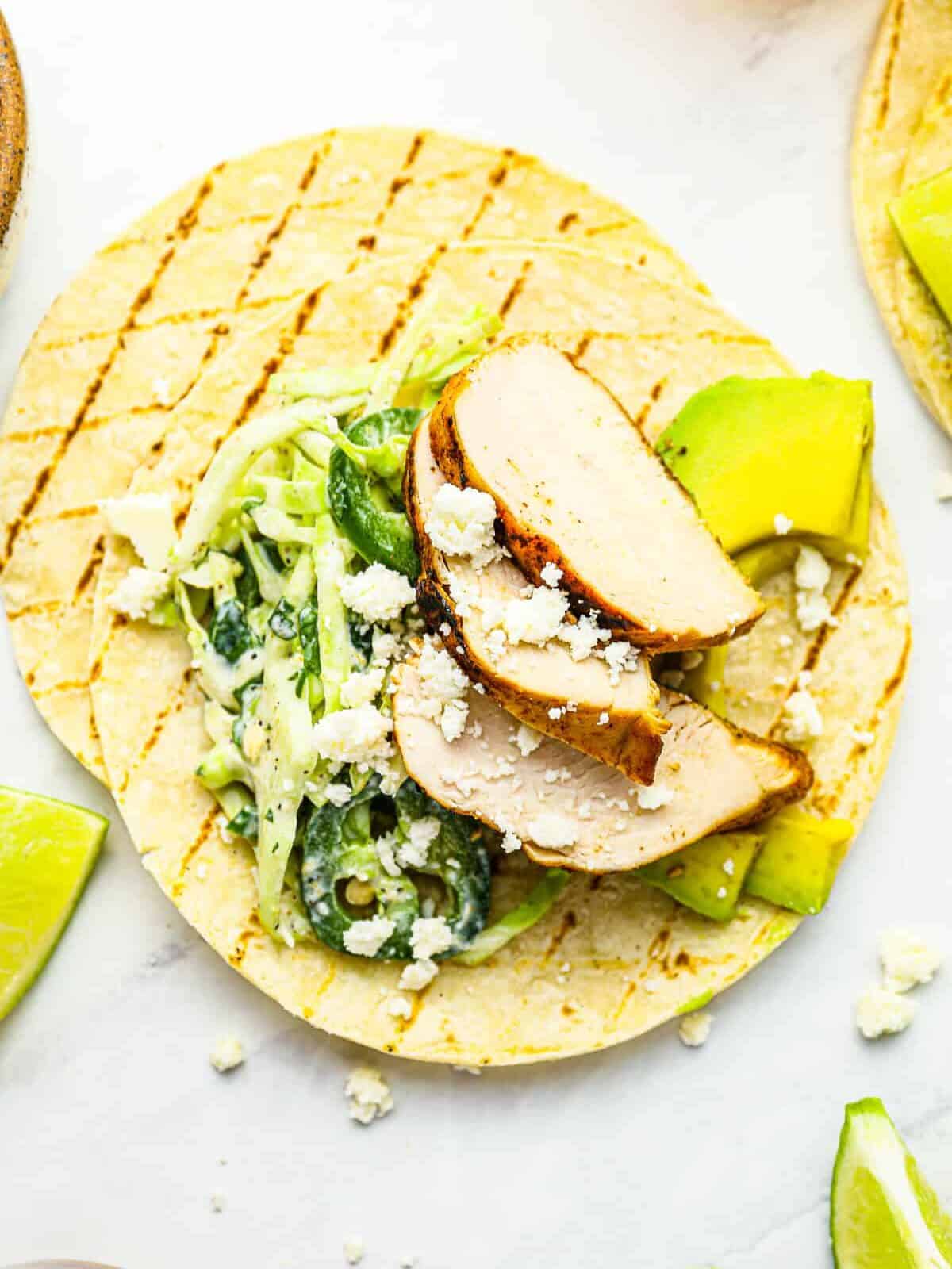 close up overhead view of an open-faced grilled chicken taco on top of another grilled tortilla.