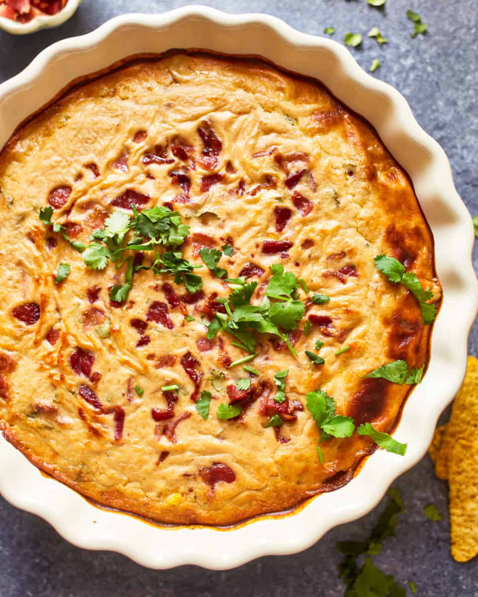 overhead view of hot corn and bacon cheese dip in a white round dish.