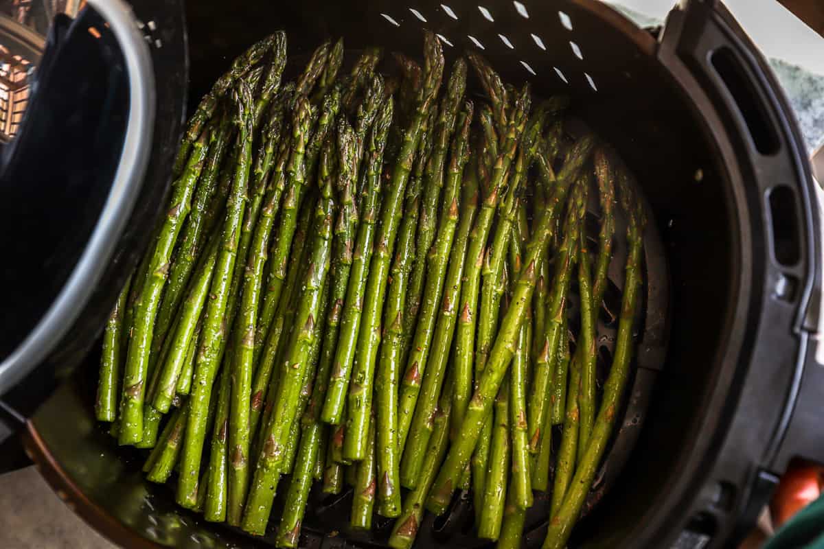 overhead view of asparagus in an air fryer basket.