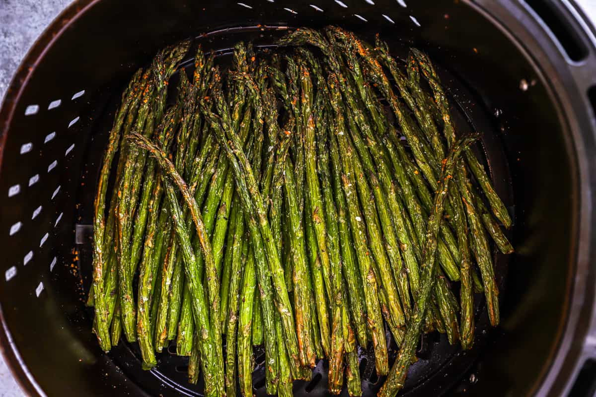 cooked asparagus in an air fryer basket.