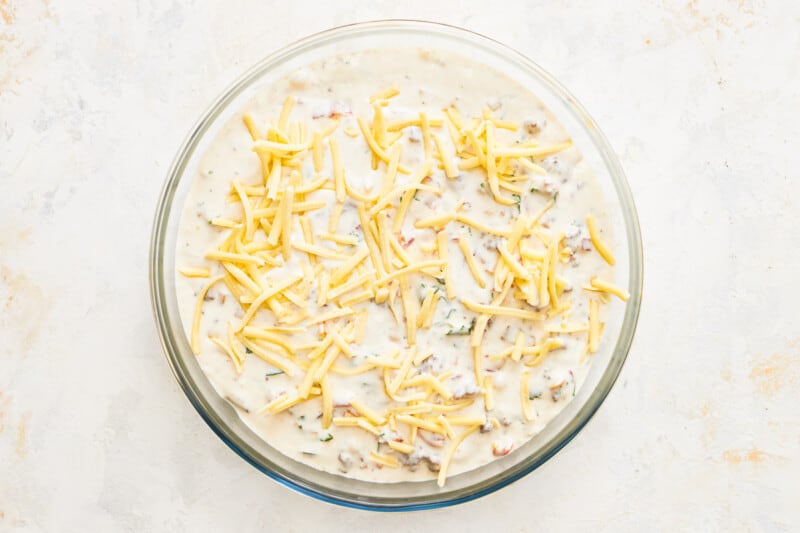 cheese sprinkled over cheeseburger dip in a round baking pan.