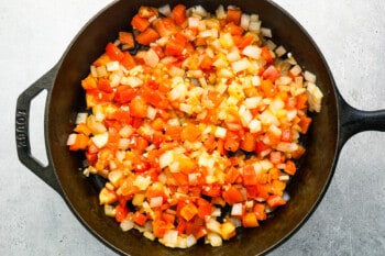 a cast iron skillet filled with chopped onions and peppers.