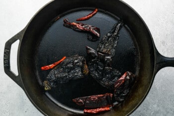 black peppers in a cast iron skillet on a gray background.