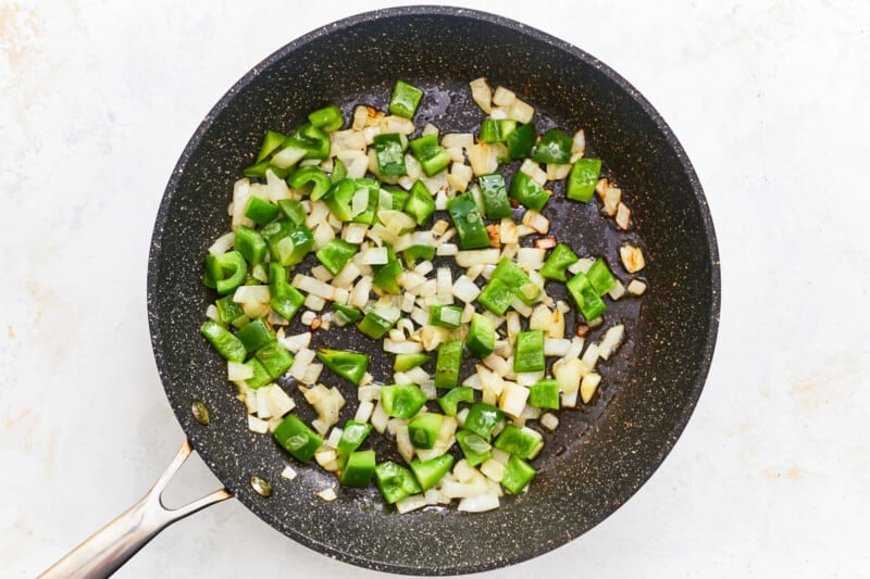 bell peppers and onions cooking a skillet