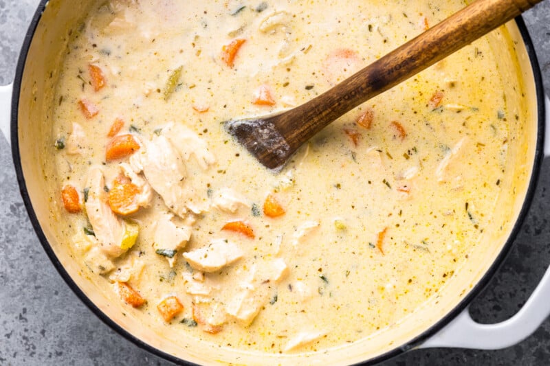 chicken noodle soup in a pan with a wooden spoon.