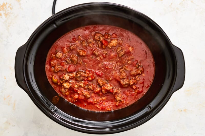 a crock pot filled with chili and meat.