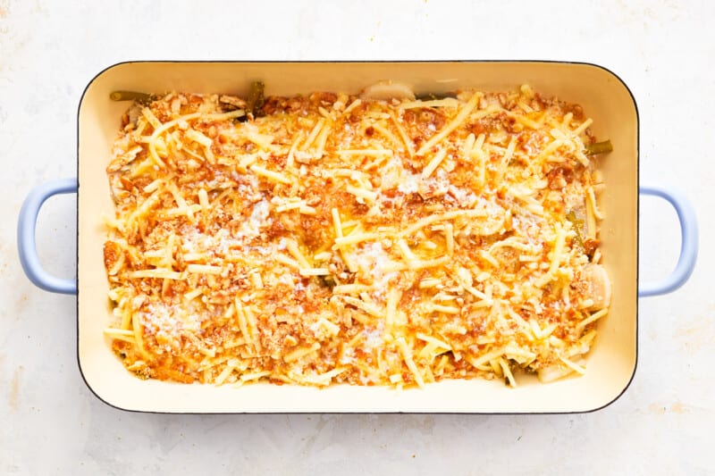 a casserole dish filled with cheese and green beans.