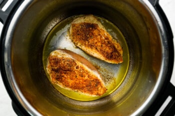 overhead view of 2 seared seasoned chicken breasts in an instant pot.
