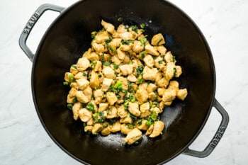 a wok filled with chicken and greens.