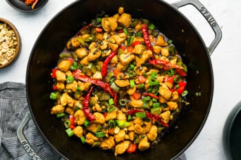 chinese chicken stir fry in a skillet with peppers and onions.