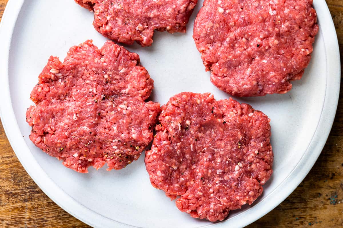 four burger patties on a plate - how to cook burgers on the stove
