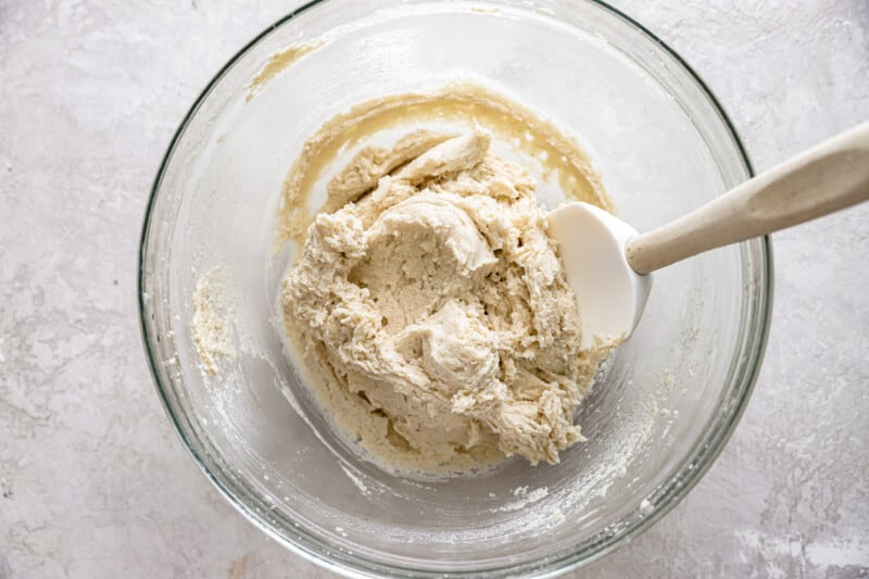 masa mixture in a glass bowl with a rubber spatula.