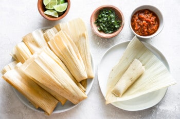 an unwrapped cooked tamale on a white plate.