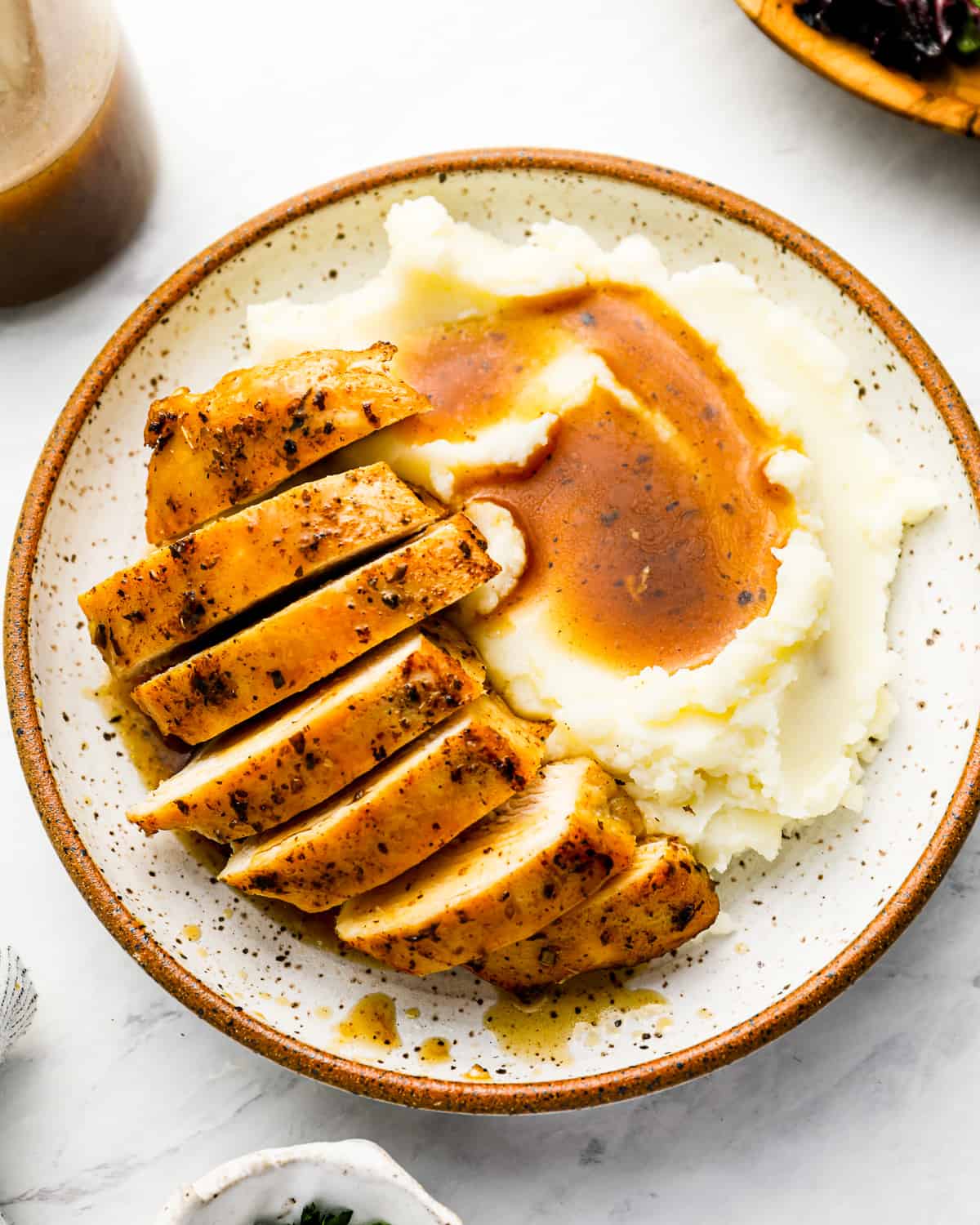 overhead view of a sliced Instant Pot chicken breast on a white plate with mashed potatoes and gravy.
