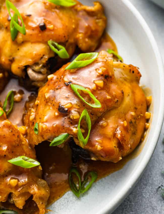 chicken thighs with sauce on a white plate.