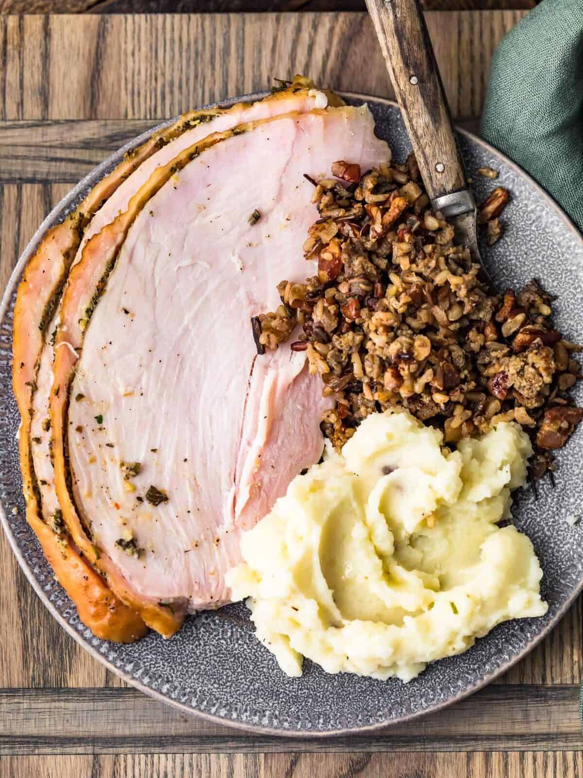a plate of smoked turkey slices with stuffing and mashed potatoes