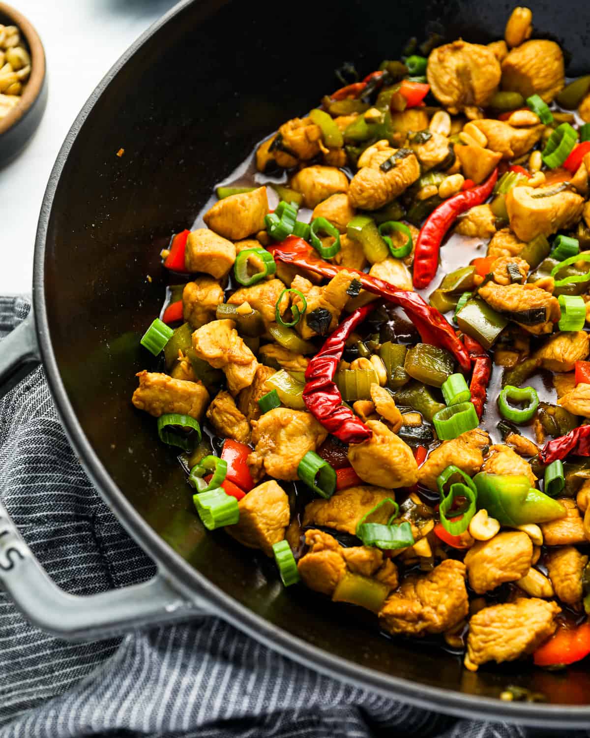 chicken and kung pao sauce in a skillet with vegetables.