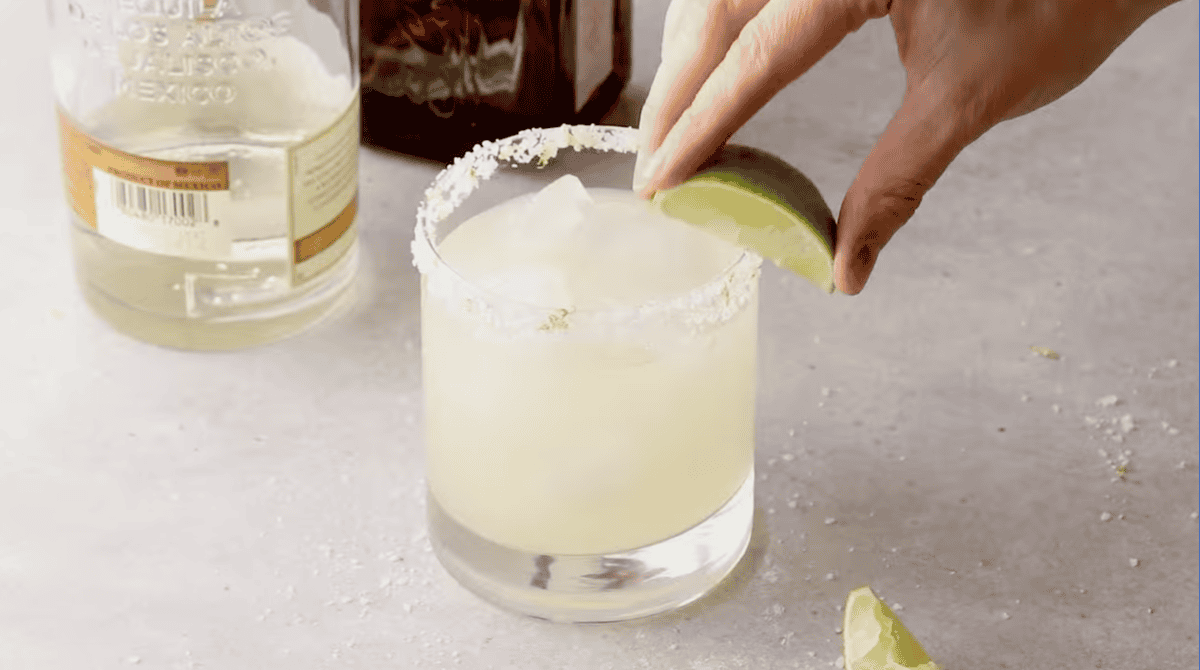garnishing a margarita with a lime wedge.