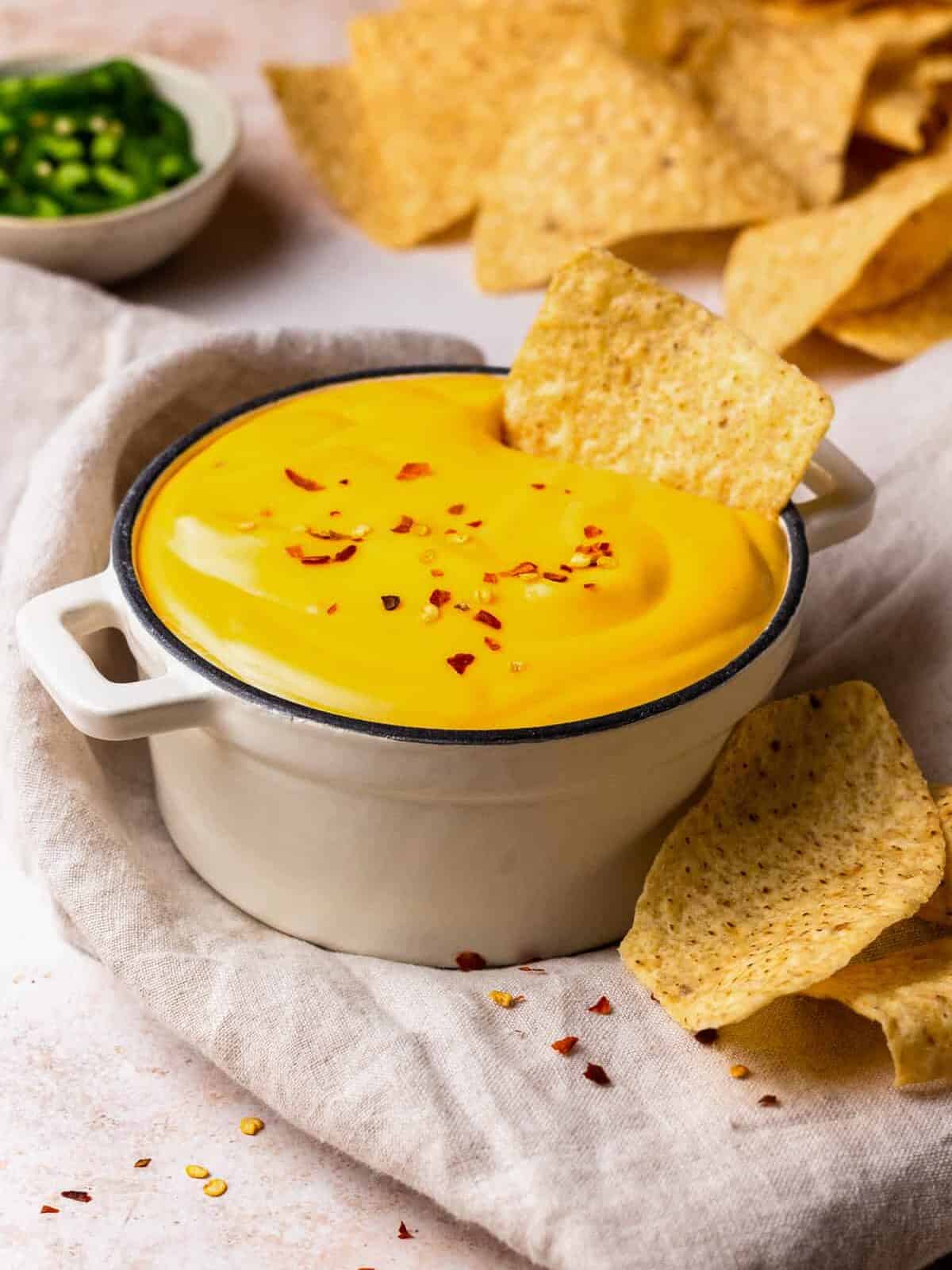 bowl of nacho cheese sauce with tortilla chips dipped in it