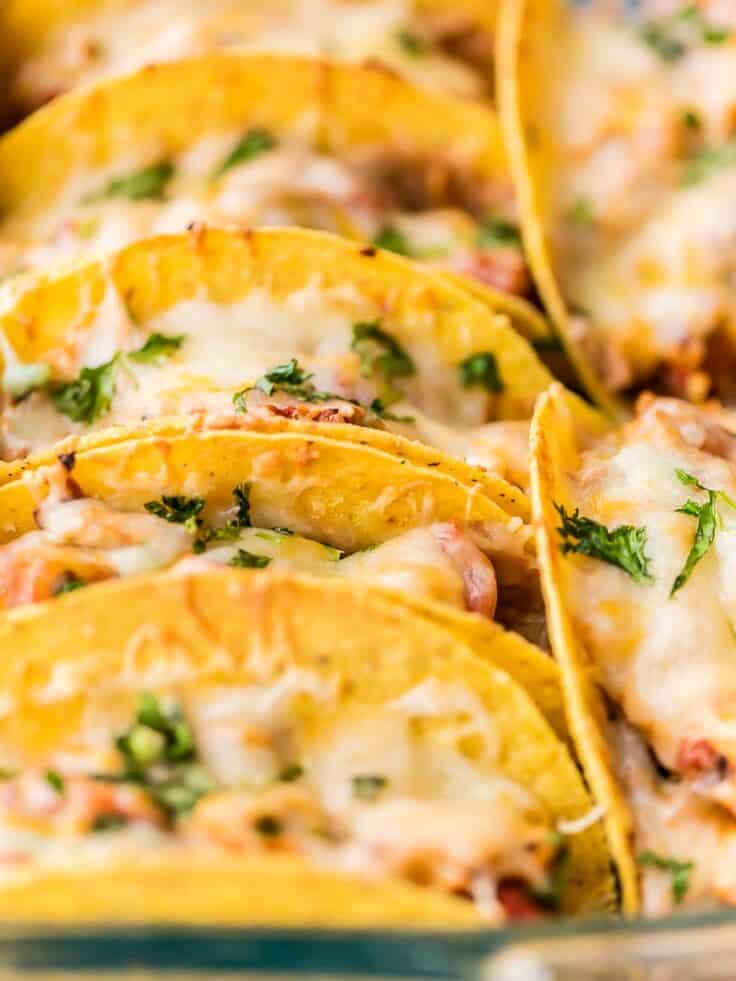 close up in easy chicken tacos in crispy taco shells, standing upright in a glass baking dish