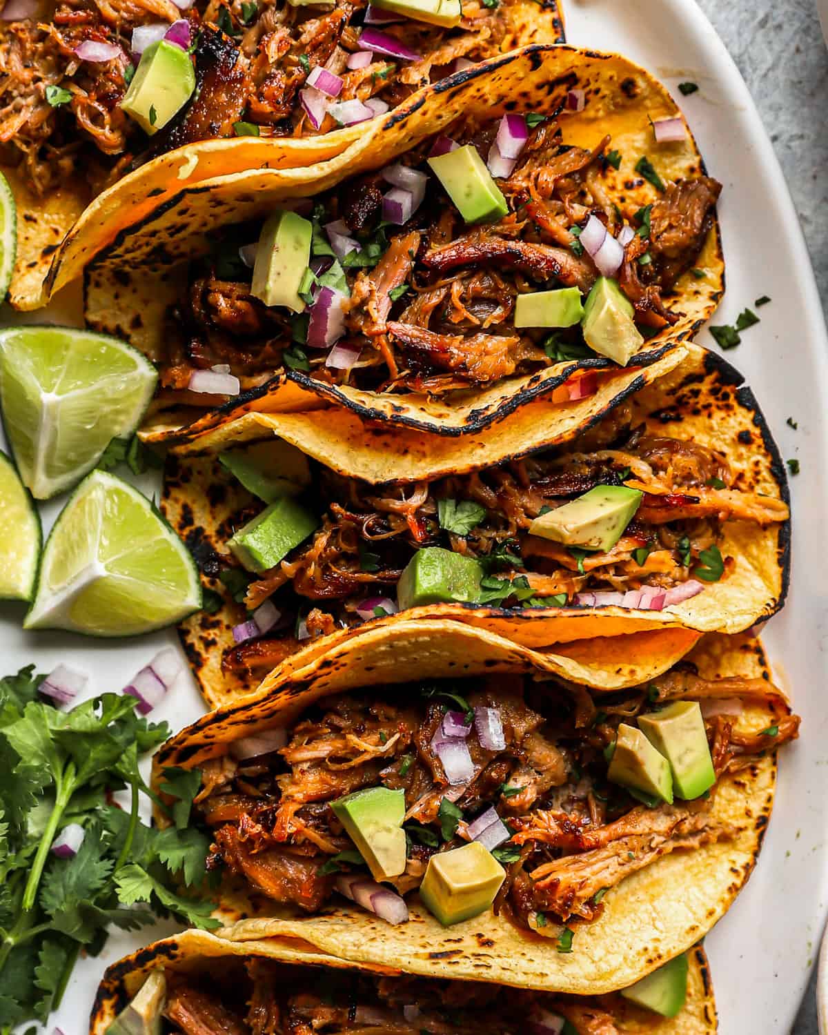 close up overhead view of Mexican carnitas tacos on a white serving platter.