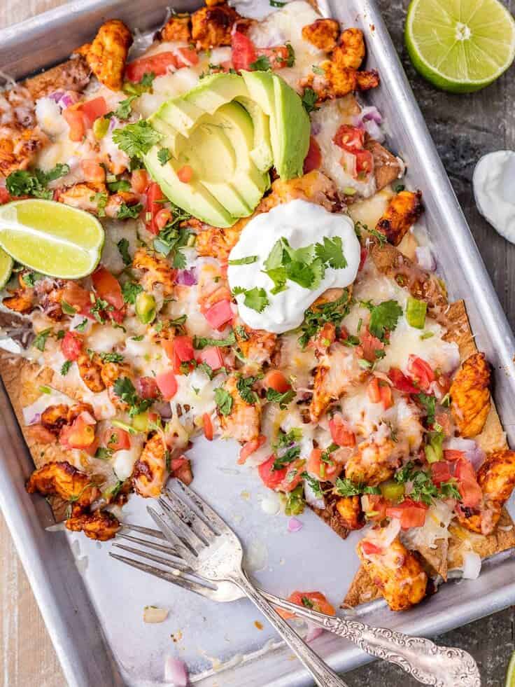 overhead view of chicken nachos on a sheet pan, with about a quarter of them gone
