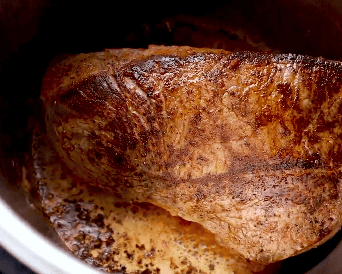 Searing the seasoned chuck roast in the Instant Pot until golden brown and crusted.