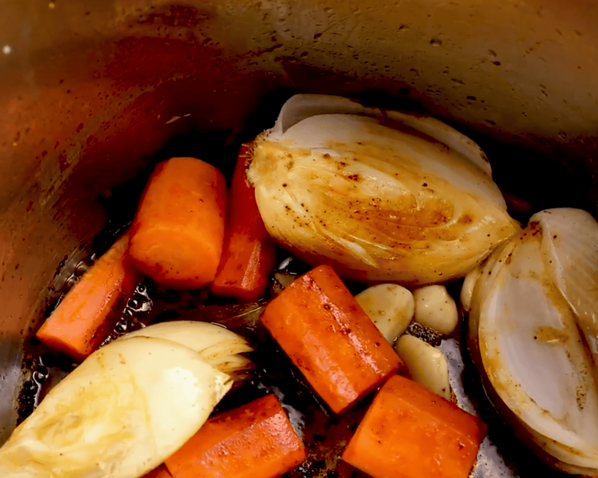 Chopped onions, carrots, and garlic sautéing in the Instant Pot after the roast has been removed.