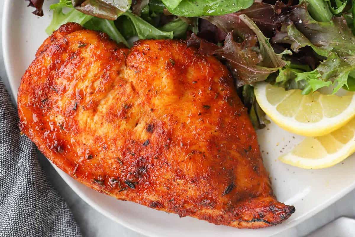 chicken breast on a white plate with salad