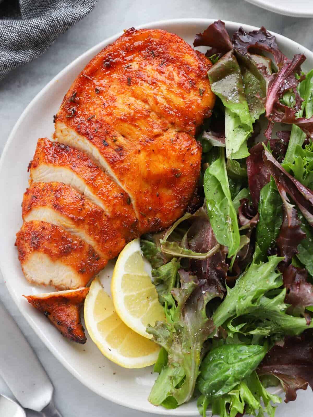 sliced chicken breast on a white plate with salad